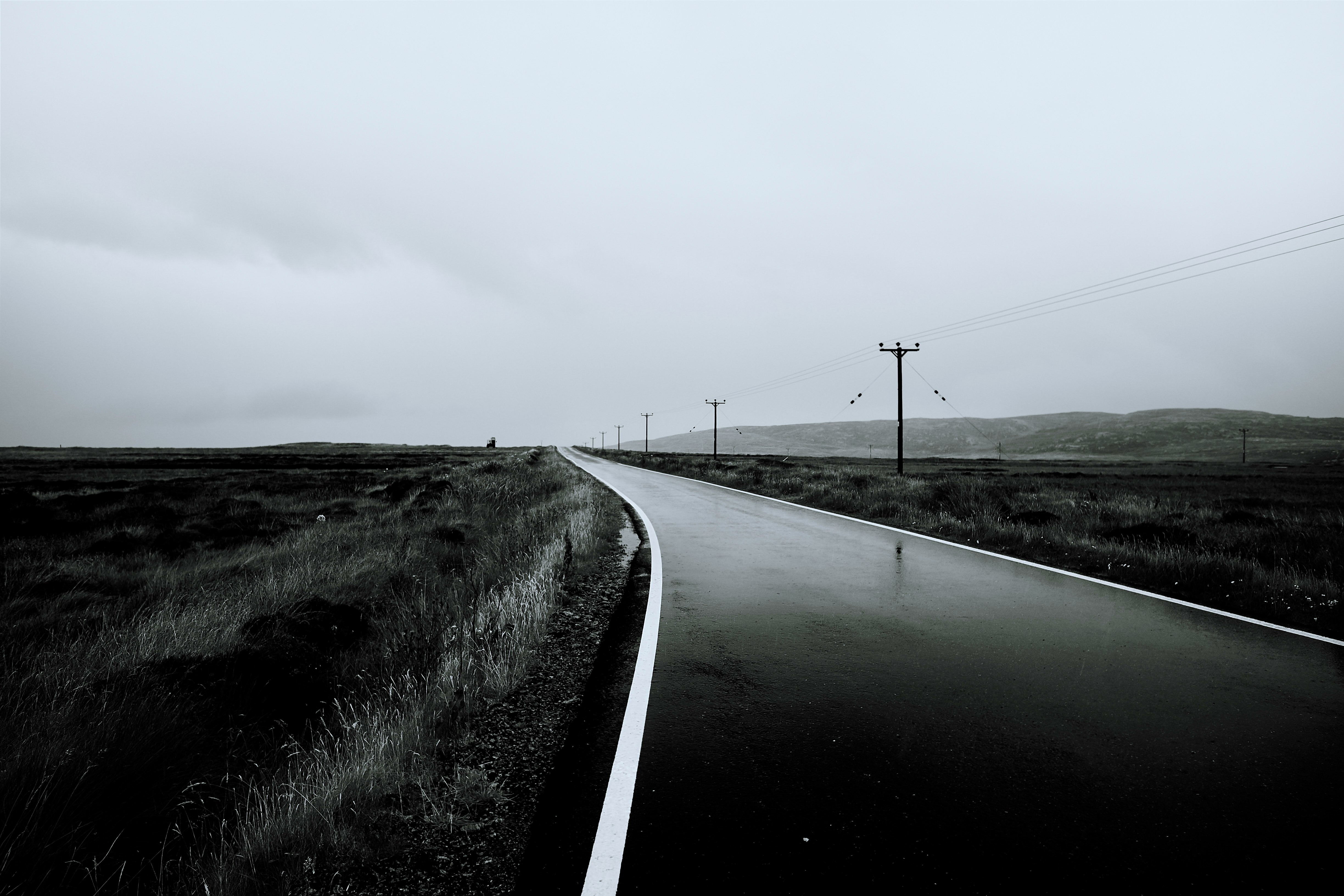 gray concrete road near mountain under white clouds at daytime